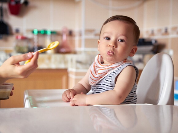 A baby being fed with infant solid foods.