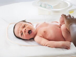 A parent changing his baby’s diaper while examing his baby poo.