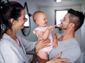 A child learning how to brush her teeth with her parents while she’s teething