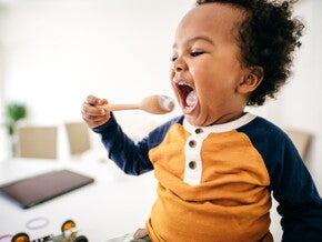 A child eating yoghurt, part of a healthy toddler diet.