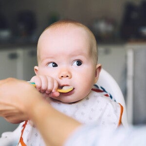 Introducing your baby’s first foods it’s an important milestone. A mother feeding with the baby’s first foods.