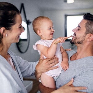 Learn some tips to apply during baby teething A child learning how to brush her teeth with her parents while she’s teething