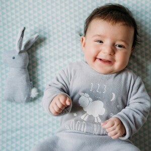 Baby’s tummy problems are common in newborns A toddler smiling in bed without any baby’s tummy problems