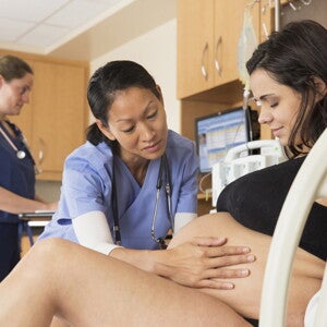 Learn more about C-sections and when they are needed during labor Doctor examining the belly of a pregnant woman before C-sections.