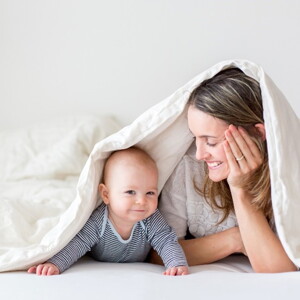 To enjoy motherhood it's vital that you do not forget yourself A mother with her baby under the sheets to enjoy motherhood.