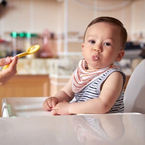 At their six months of age your baby should be ready for infant solid food. A baby being fed with infant solid foods.