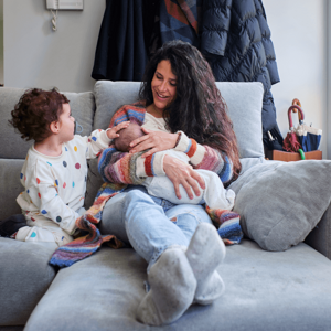 Get to know the breastfeeding benefits for you and your baby. A mom enjoying breastfeeding benefits with her baby alongside her toddler.