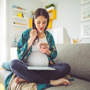 Pregnancy cravings are a common part of the gestation process A woman indulging her pregnancy cravings in her home.