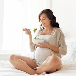 Discover the best pregnancy healthy food for you A woman eating some pregnancy healthy food.