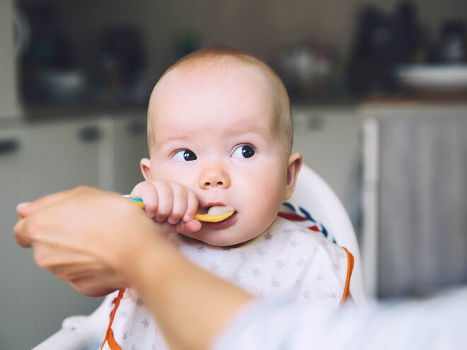 A mother feeding with the baby’s first foods.