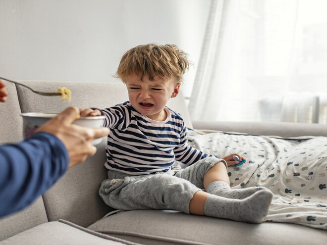 A toddler being a picky eater and rejecting food from his parent. 