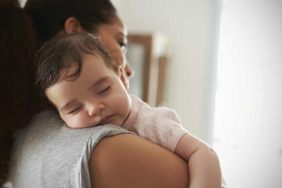 A child sleeping in the arms of his mom after a baby massage.