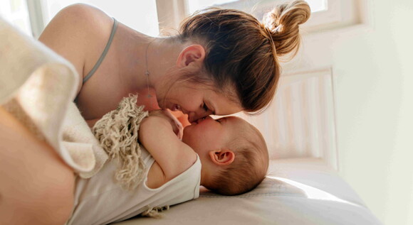 A mom enjoying quality time with his baby in bed.