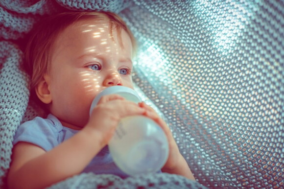 A toddler drinking milk from his bottle.
