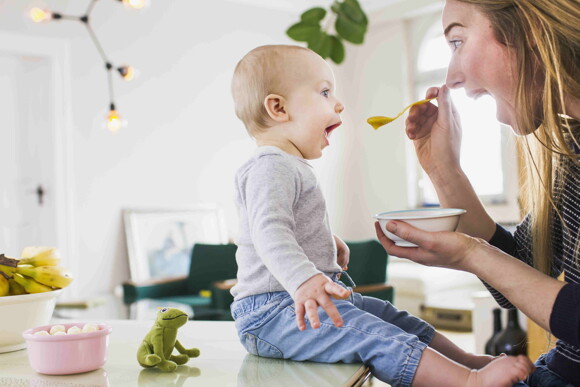 A baby receiving new food from his mother avoiding picky eating habits. 