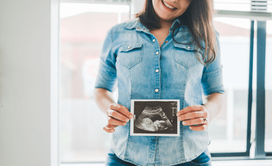 A woman with the picture of and echo in her belly after the first trimester.